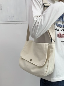 Detail of off-white canvas messenger bag with adjustable strap and vintage metal snap