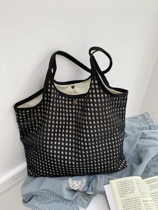 Close-up of black mesh tote bag with retro metal buckle and off-white canvas lining