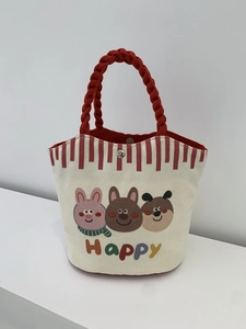 Detail of canvas tote bag showing red braided handles and secure metal magnetic snap closure