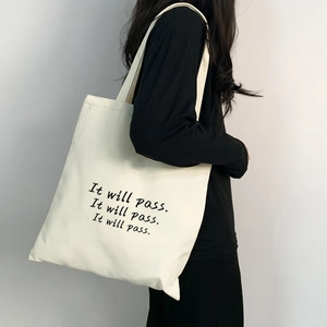 Minimalistische weiße Canvas-Tasche mit schwarzem Textdruck, getragen von einem Modell