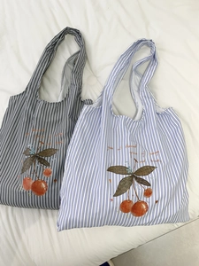 Detail of striped canvas tote bags with cherry prints in black and blue patterns