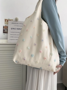 Detailed macro of the 3D macaron flower patches on this beige canvas tote bag for women