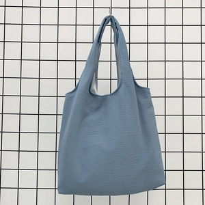 Detail of light blue canvas tote bag with wide integrated handle on a metal rack