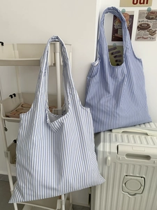 Détail d'un sac cabas à rayures bleues et blanches montrant le tissu et la large bandoulière
