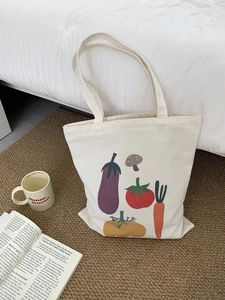 Dettaglio di una borsa tote in tela con stampe di verdure e manici lunghi resistenti