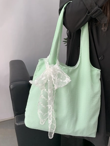 Detail of light green striped canvas tote bag with a large white lace bow accent