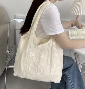 Close-up of floral embroidery on off-white canvas tote bag with textured fabric detail