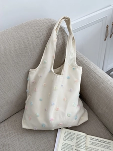 Detailed close-up of 3D floral embroidery on an elegant off-white canvas tote bag