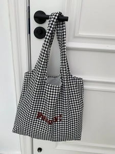 Detail of red Peachy embroidery on a black and white gingham canvas tote bag