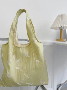 Close-up of light green canvas tote with white floral embroidery and crinkled texture