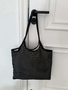 Detail of black and white checkerboard tote bag with metal snap button and black straps