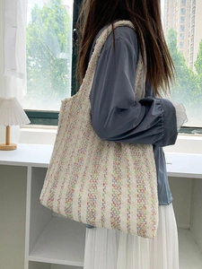 Close-up of a model wearing a knit tote bag with colorful vertical stripes and texture