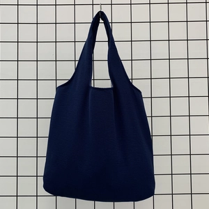 Detail of heavy navy canvas tote bag with integrated handles on a metal grid display