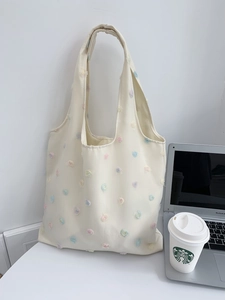 Detail of floral embroidery on cream canvas tote bag with wide shoulder strap