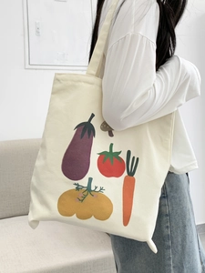 Dettaglio di una grande borsa tote in tela con illustrazioni di verdure e tracolle doppie