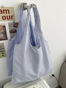 Sac fourre-tout en toile à rayures bleues et blanches suspendu dans un intérieur