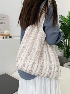 Close-up of white crochet tote bag with colorful neon stripes and intricate lace patterns