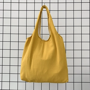Detail of a bright yellow canvas tote bag showing fine fabric texture and sturdy handle