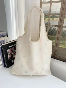 Detailed view of beige canvas tote bag with 3D floral embroidery and mesh flower accents