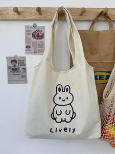 Détail du sac cabas en toile crème avec motif de lapin animé suspendu à un crochet mural