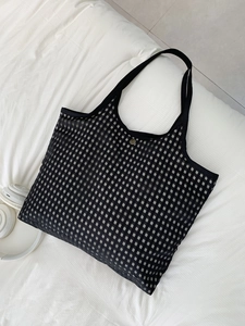 Detailed top view of a black checkered mesh tote bag with a metal button closure