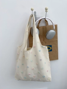 Detail of embroidered floral 3D pattern on cream white canvas tote bag with long straps