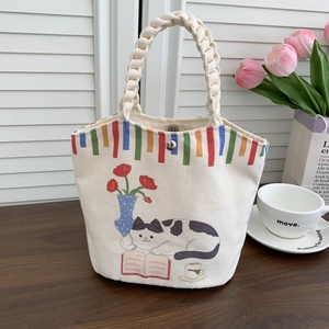 Detail of canvas bucket bag showing the woven handle and cute cartoon cat illustration