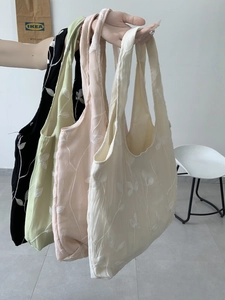 Close-up of four lace canvas tote bags with leaf embroidery in multiple colors