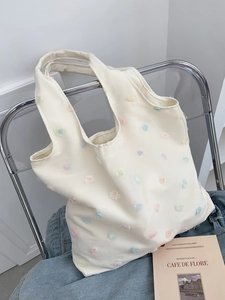 Detail of floral embroidery on cream white canvas tote bag with 3D applique flowers