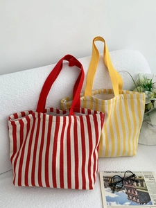 Detail of red and yellow striped canvas tote bags with zippers on a textured sofa