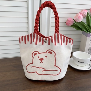 Detail of canvas bucket bag with cute bear print and red woven rope handles