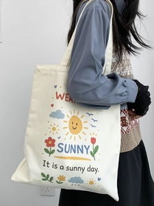 Dettaglio di una borsa tote in tela bianco crema con stampe a cartoni su una modella