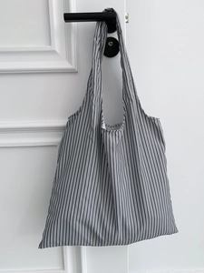 Détail d'un grand sac bandoulière à rayures noires et blanches avec poignée souple