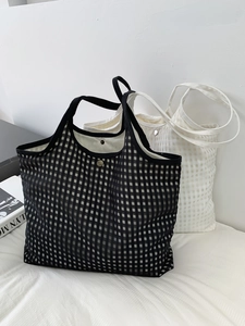 Detail view of checkered mesh tote bags with metal snap buttons on a white bed
