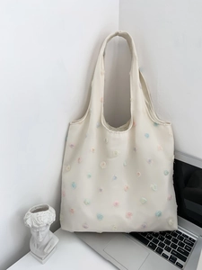 Artistic cream canvas tote bag with 3D floral embroidery and minimalist laptop background