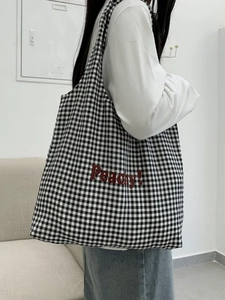 Detail of checkered canvas tote bag with red Peachy text print and large capacity