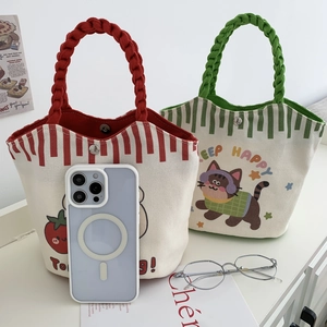 Detail of canvas bucket bags with strawberry prints and woven rope handles for daily use