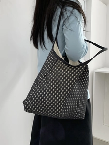 Detail view of large checkerboard mesh tote bag with black shoulder straps for women