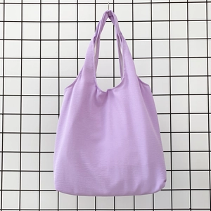 Close-up of a light purple cotton canvas tote bag hanging on a minimalist metal grid