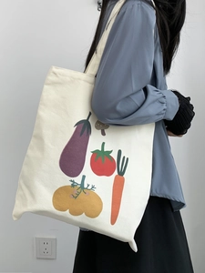 Dettaglio di una borsa tote in tela con stampe di verdure colorate indossata da un modello