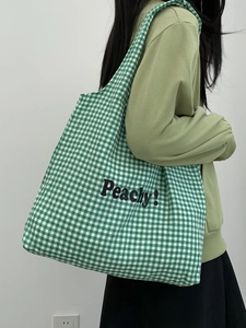 Detail of green and white plaid canvas tote bag with black Peachy! text print