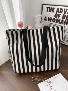 Detail of striped canvas tote bag with black strap in a minimalist lifestyle setting
