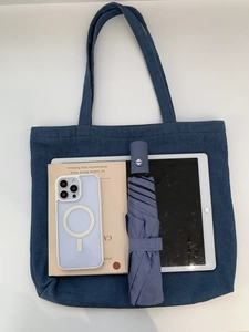Macro shot of large capacity blue denim tote bag interior holding books and a tablet