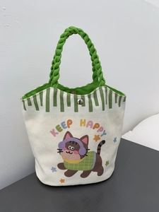 Small canvas tote bag with cartoon cat illustration and green woven handles with snap closure
