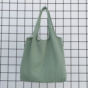 Detailed view of light green canvas tote bag hanging on a industrial black mesh wall