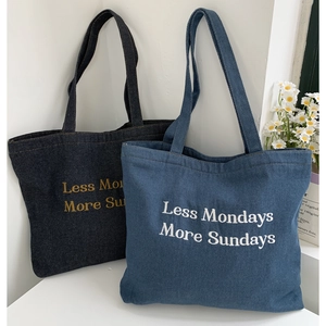 Detail of embroidered slogan on denim tote bags with thick texture and stitching