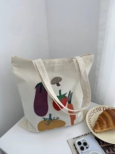 Dettaglio ravvicinato della borsa tote in tela crema con motivi di verdure realistici e trama
