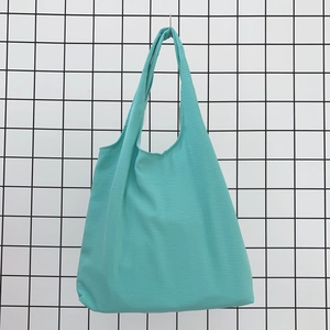 Detail of teal cotton tote bag showing sturdy seamless handles and canvas fabric texture