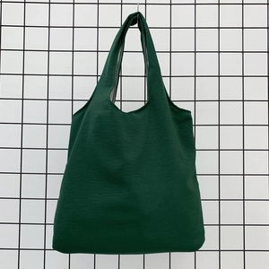 Detail of dark green canvas tote bag fabric texture and wide shoulder strap