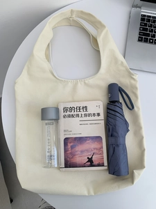 Détail de la capacité du sac fourre-tout en toile blanc cassé avec livres et gourde
